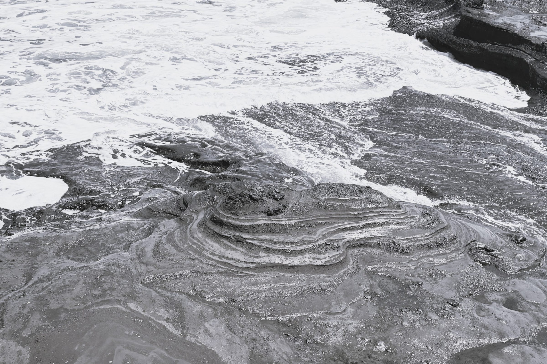 Surf washing over layered shoreline rock